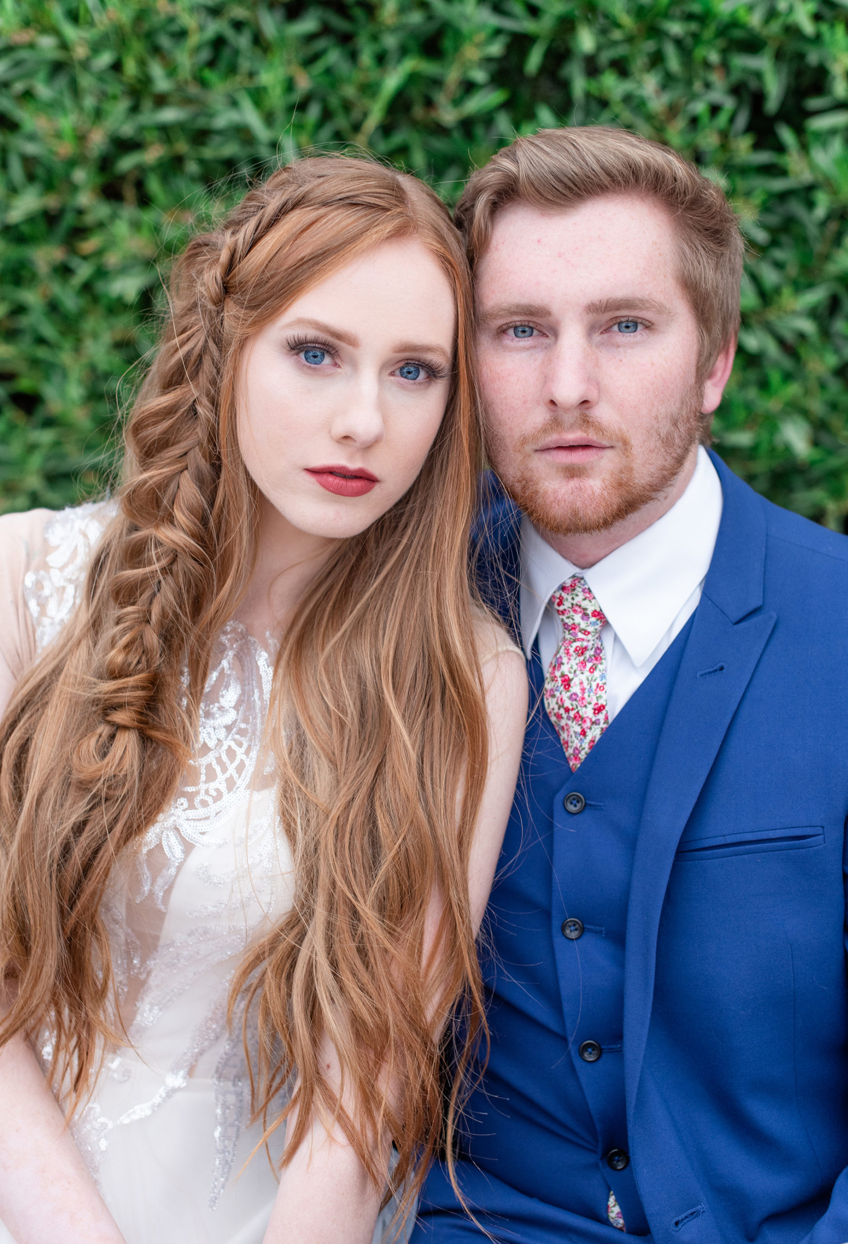 red headed bride and groom stare at camera with blue eyes